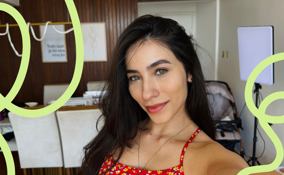 Foto no formato selfie de Isadora, mulher branca, com cabelos pretos e olhos claros. Ao fundo, o que parece ser um consultório médico.